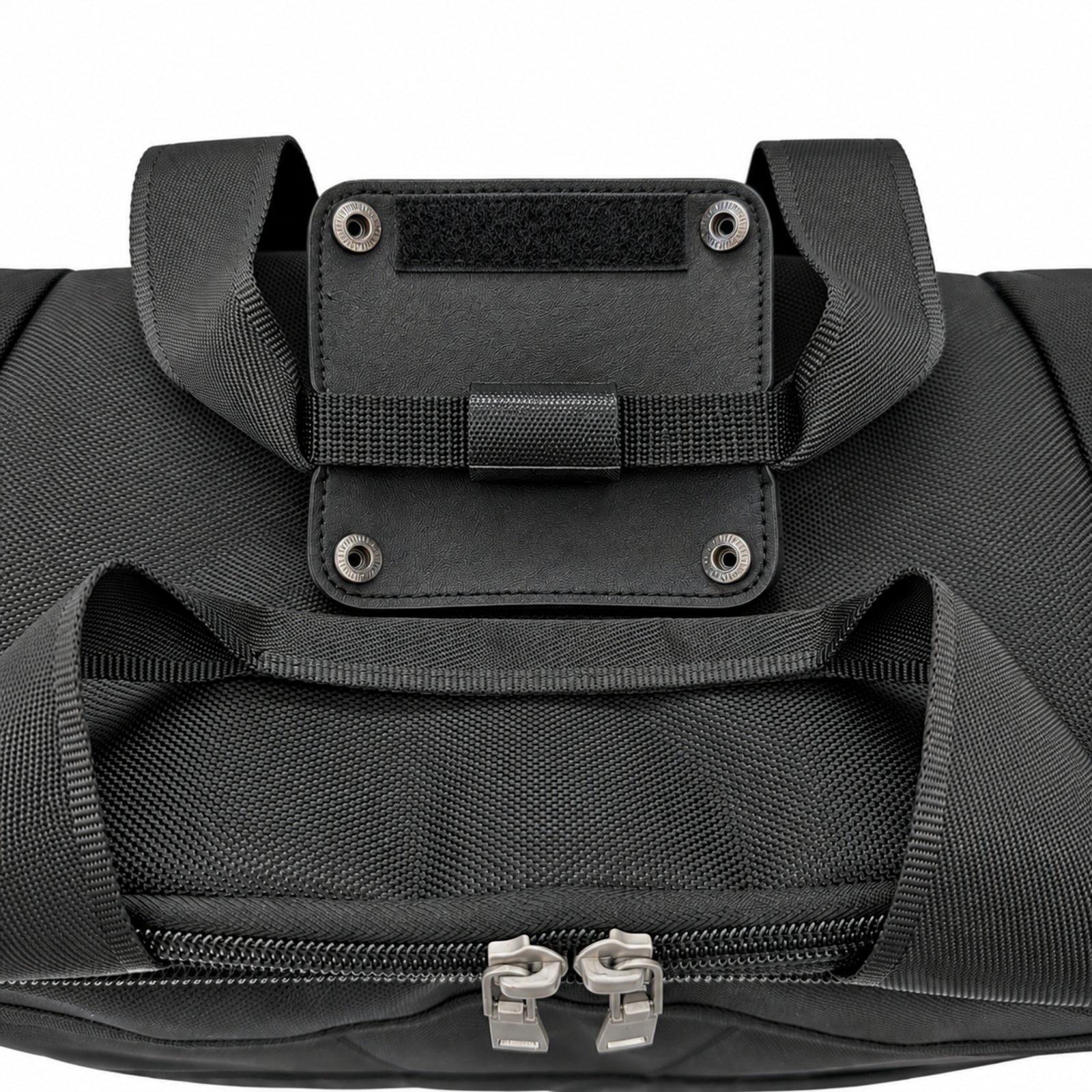 Close-up of a black duffel bag showing a front zippered compartment with dual silver zipper pulls and a black webbing handle attachment with metal rivets on a white background.